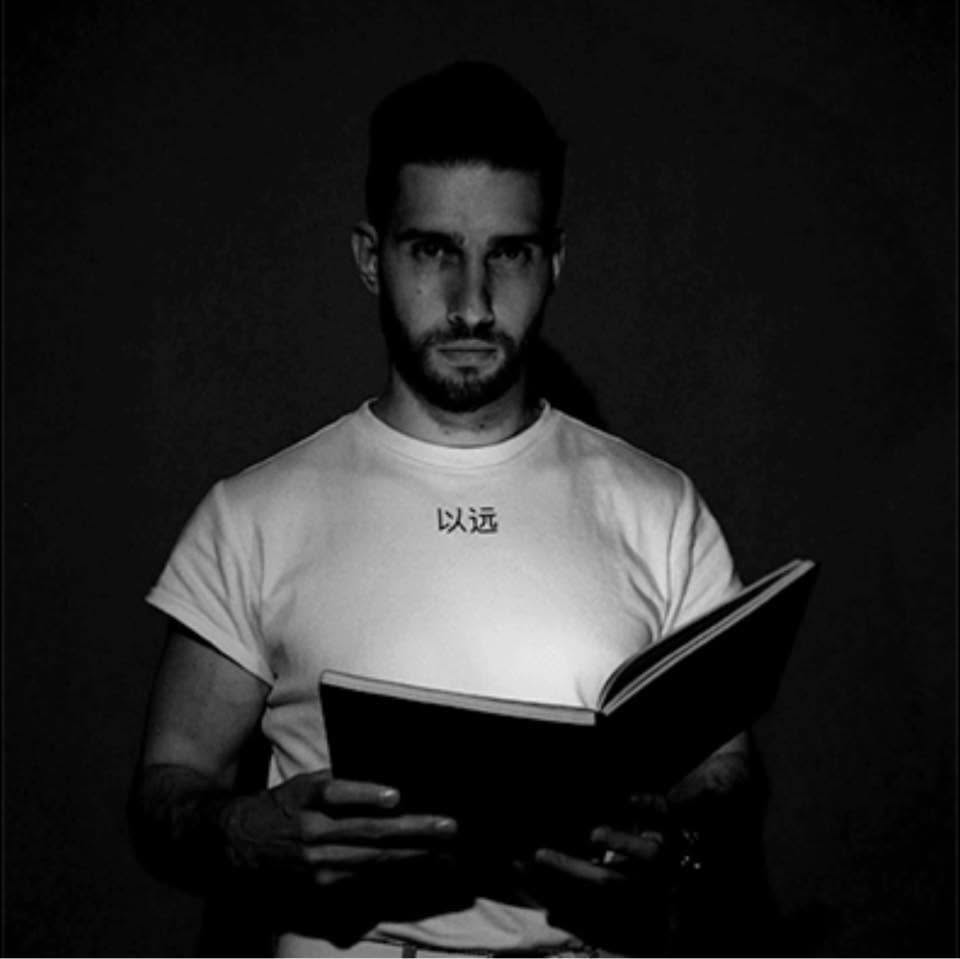 A black and white portrait of a man holding an open book, wearing a white t-shirt with Chinese characters printed on the chest against a dark background. Gito Art artists - Limited Wall Art