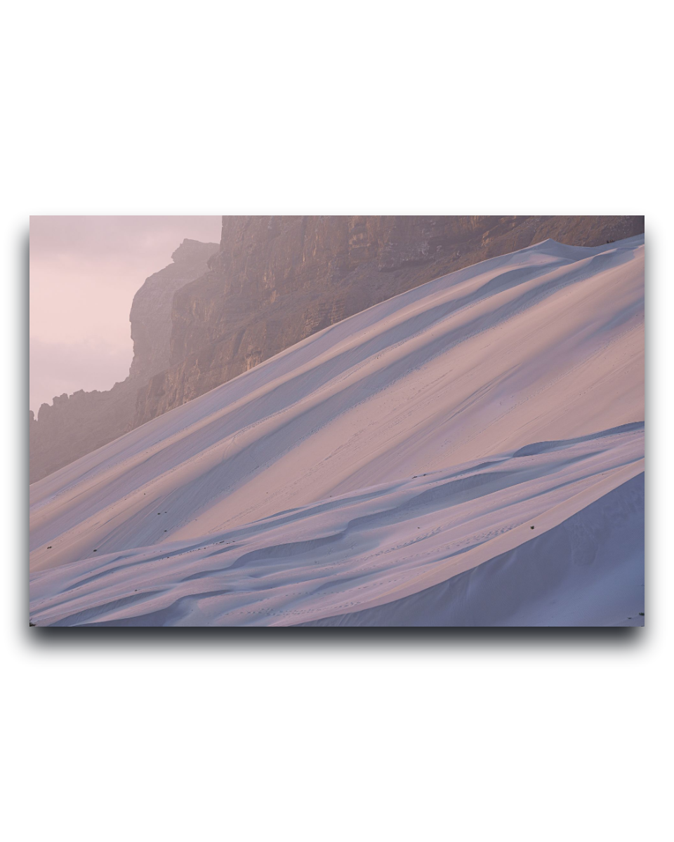 Gito.Art - Exclusive Art Print - Photography by Delyan Markov
A rectangular wall art print or canvas showing a snowy mountain slope with soft pinkish light and dark rock cliffs, displayed against a plain white background.