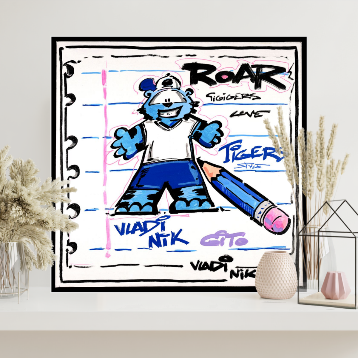 Gito Fine Art Print - Art Vladi Vl Comics - Tigers
A framed art print featuring a cartoon blue bear character with the text 'ROAR" and 'VIADI NIK' on a lined notebook-style background, displayed on a shelf with decorative dried grasses and small vases.